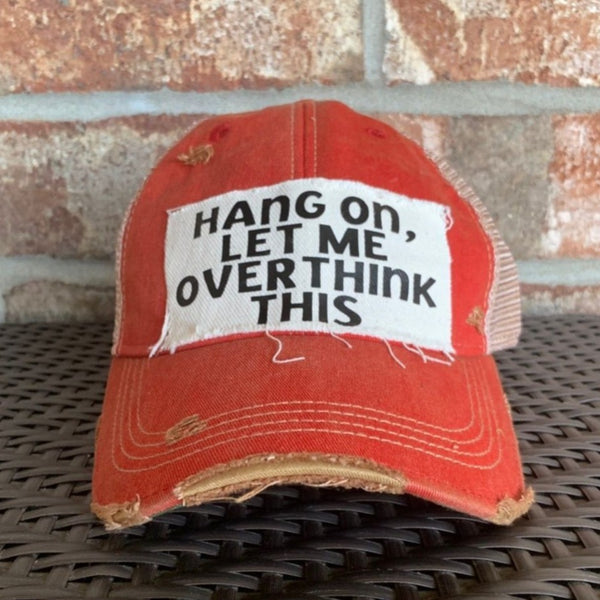 Hang On Let Me Overthink This hat by BohoGroove with black Hang On Let Me Overthink This lettering on a distressed off-white patch on a red vintage distressed snapback trucker hat.