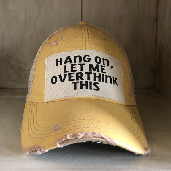 Hang On Let Me Overthink This hat by BohoGroove with black Hang On Let Me Overthink This lettering on a distressed off-white patch on a yellow vintage distressed snapback trucker hat.