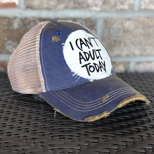 Left side view of I Can't Adult Today hat by BohoGroove with black lettering on a distressed off-white patch on a royal blue vintage distressed snapback trucker hat.
