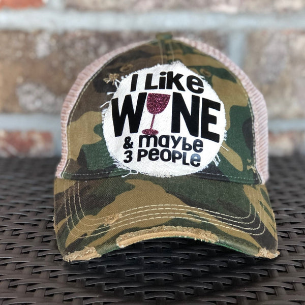 I Like Wine and Maybe 3 People hat by BohoGroove with black lettering and a glitter wine glass graphic on a distressed off-white patch on a camo vintage distressed snapback.