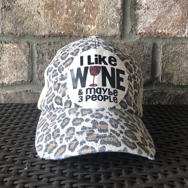 I Like Wine and Maybe 3 People hat by BohoGroove with black lettering and a glitter wine glass graphic on a distressed off-white patch on a leopard vintage distressed snapback.