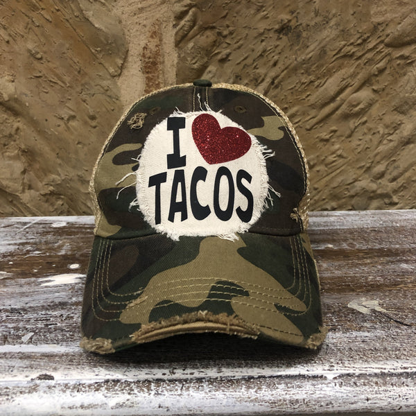 Camo distressed snapback hat featuring an off-white I Love Tacos patch with a red glitter heart