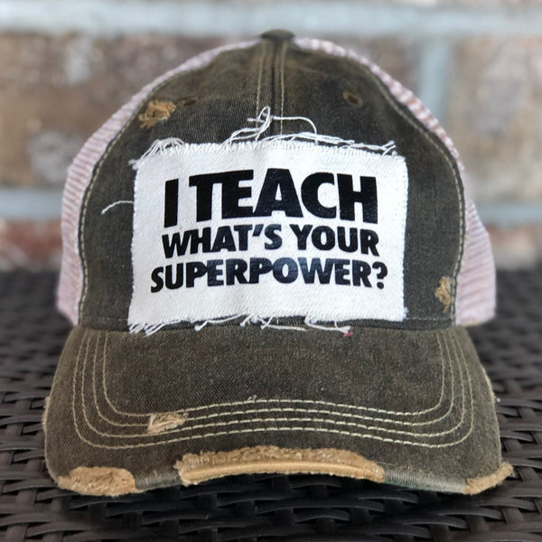 I Teach What's Your Superpower hat by BohoGroove with black lettering on a distressed off-white patch on a black vintage distressed snapback trucker hat.