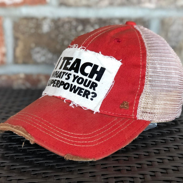 Right side view of I Teach What's Your Superpower hat by BohoGroove with black lettering on a distressed off-white patch on a red vintage distressed snapback trucker hat.
