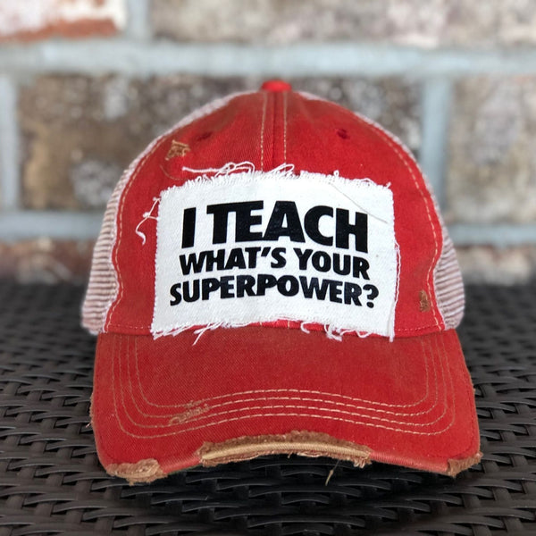 I Teach What's Your Superpower hat by BohoGroove with black lettering on a distressed off-white patch on a red vintage distressed snapback trucker hat.