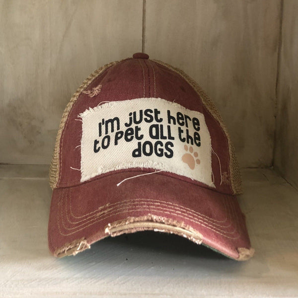 I'm Just Here to Pet All the Dogs hat by BohoGroove with black I'm Just Here to Pet All the Dogs lettering and paw print graphic on a distressed off-white patch on a black vintage distressed snapback.
