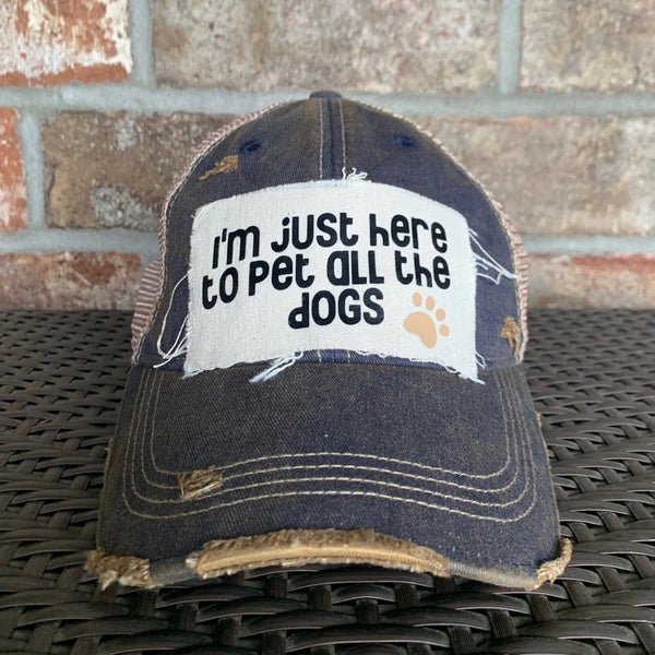 I'm Just Here to Pet All the Dogs hat by BohoGroove with black I'm Just Here to Pet All the Dogs lettering and paw print graphic on a distressed off-white patch on a navy blue vintage distressed snapback.
