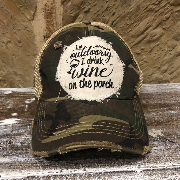 I'm Outdoorsy I Drink Wine on the Porch hat by BohoGroove with black lettering and wine glass graphic on a distressed off-white patch on a camo vintage distressed snapback trucker hat.