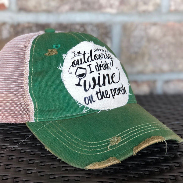 Left side view of a green vintage distressed snapback trucker hat by BohoGroove featuring a distressed off-white patch with black I'm Outdoorsy I Drink Wine on the Porch lettering and wine glass graphic.