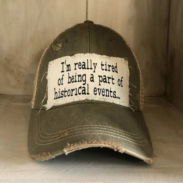 I’m Really Tired of Being Part of Historical Events hat by BohoGroove with black lettering on a distressed off-white patch on an olive vintage distressed snapback.

