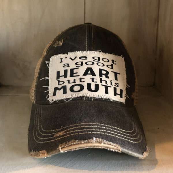 I've Got a Good Heart, but This Mouth hat by BohoGroove with black lettering on a distressed off-white patch on a black vintage distressed snapback trucker hat.