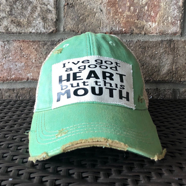 I've Got a Good Heart, but This Mouth hat by BohoGroove with black lettering on a distressed off-white patch on a mint vintage distressed snapback trucker hat.