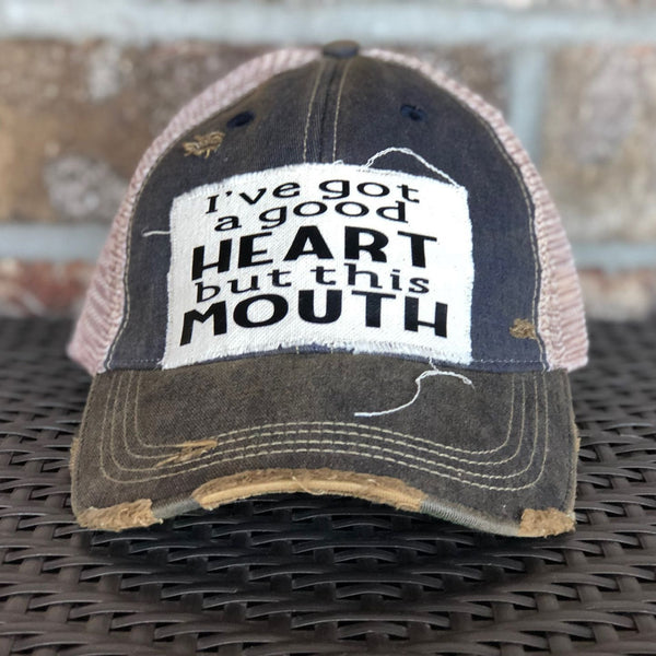 I've Got a Good Heart, but This Mouth hat by BohoGroove with black lettering on a distressed off-white patch on a navy blue vintage distressed snapback trucker hat.