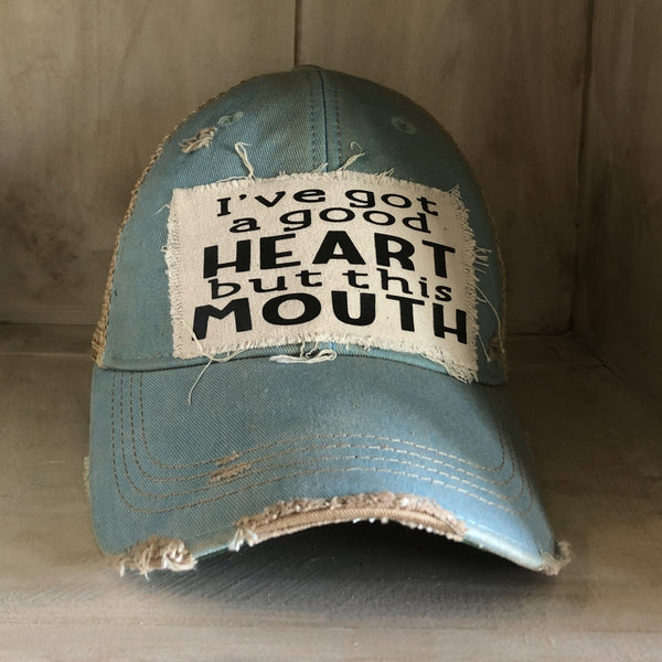I've Got a Good Heart, but This Mouth hat by BohoGroove with black lettering on a distressed off-white patch on an ocean blue vintage distressed snapback trucker hat.