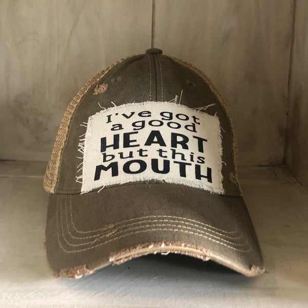 I've Got a Good Heart, but This Mouth hat by BohoGroove with black lettering on a distressed off-white patch on an olive vintage distressed snapback trucker hat.
