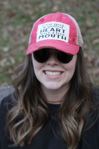 I've Got a Good Heart, but This Mouth hat by BohoGroove with black lettering on a distressed off-white patch on a pink vintage distressed snapback trucker hat on model.
