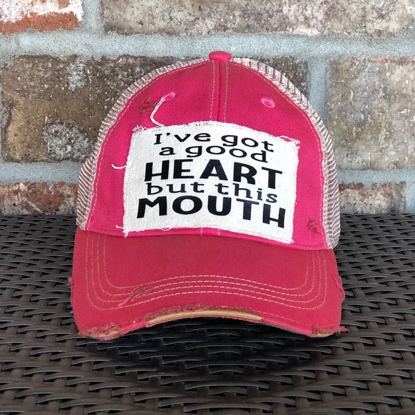 I've Got a Good Heart, but This Mouth hat by BohoGroove with black lettering on a distressed off-white patch on a pink vintage distressed snapback trucker hat.