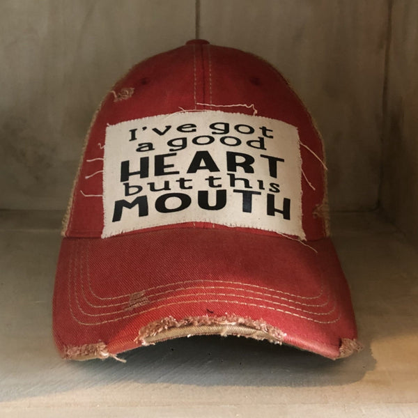 I've Got a Good Heart, but This Mouth hat by BohoGroove with black lettering on a distressed off-white patch on a red vintage distressed snapback trucker hat.
