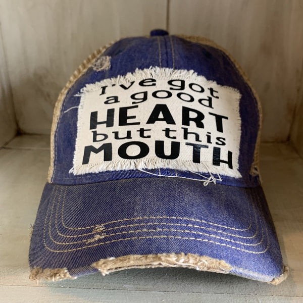 I've Got a Good Heart, but This Mouth hat by BohoGroove with black lettering on a distressed off-white patch on a royal blue vintage distressed snapback trucker hat.