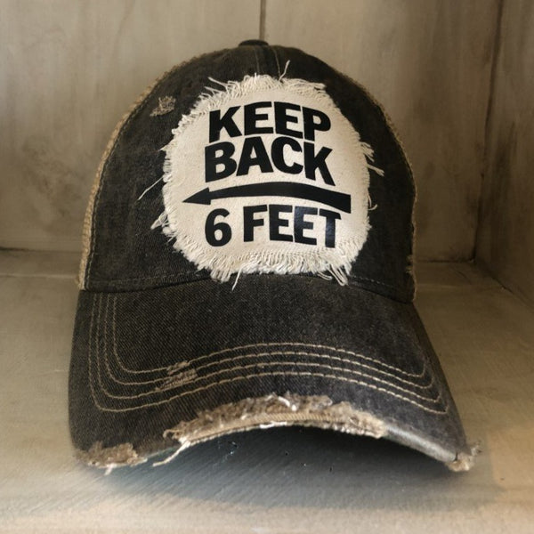 Keep Back 6 Feet hat by BohoGroove with black lettering and arrow graphic on a distressed off-white patch on a black vintage distressed snapback trucker hat.