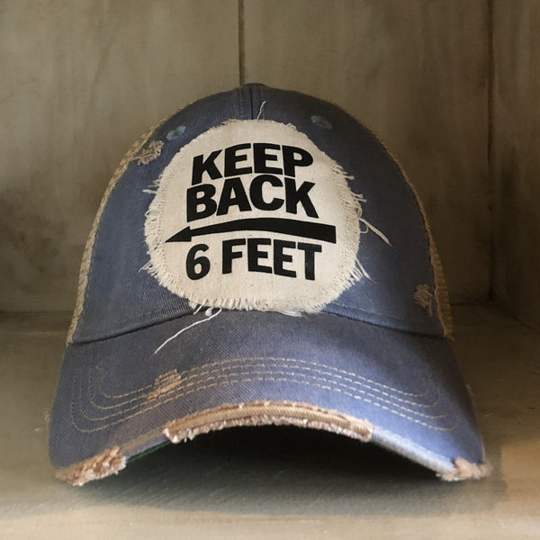 Keep Back 6 Feet hat by BohoGroove with black lettering and arrow graphic on a distressed off-white patch on a light blue vintage distressed snapback trucker hat.