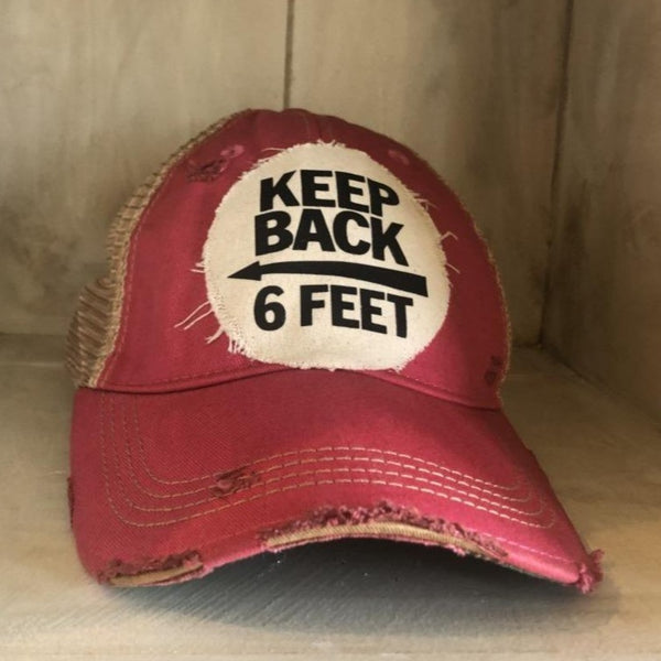 Keep Back 6 Feet hat by BohoGroove with black lettering and arrow graphic on a distressed off-white patch on a pink vintage distressed snapback trucker hat.