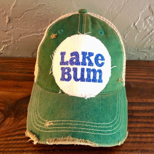 Lake Bum hat by BohoGroove with blue glitter Lake Bum lettering on distressed off-white patch on a green vintage distressed snapback.