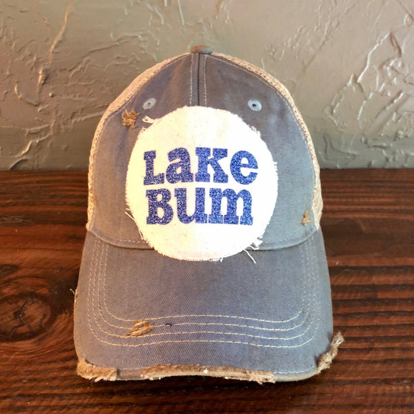 Lake Bum hat by BohoGroove with blue glitter Lake Bum lettering on distressed off-white patch on a light blue vintage distressed snapback.
