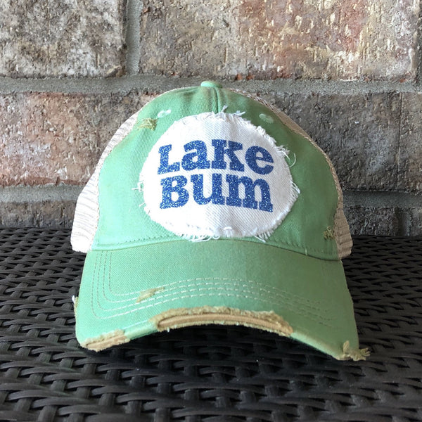 Lake Bum hat by BohoGroove with blue glitter Lake Bum lettering on distressed off-white patch on a mint green vintage distressed snapback.