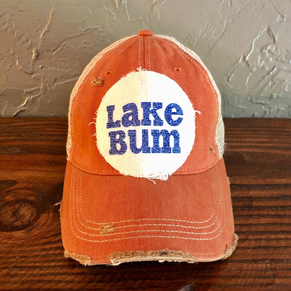 Lake Bum hat by BohoGroove with blue glitter Lake Bum lettering on distressed off-white patch on an orange vintage distressed snapback.