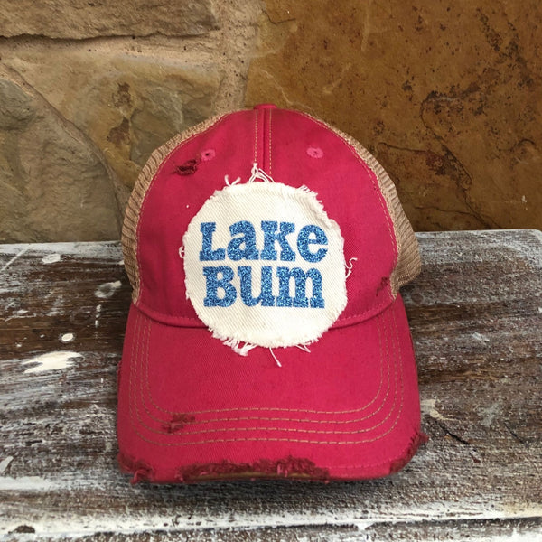 Lake Bum hat by BohoGroove with blue glitter Lake Bum lettering on distressed off-white patch on a pink vintage distressed snapback.