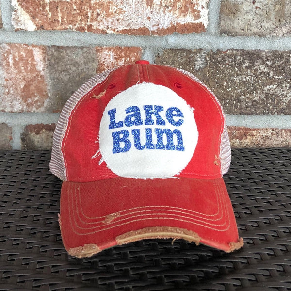 Lake Bum hat by BohoGroove with blue glitter Lake Bum lettering on distressed off-white patch on a red vintage distressed snapback.