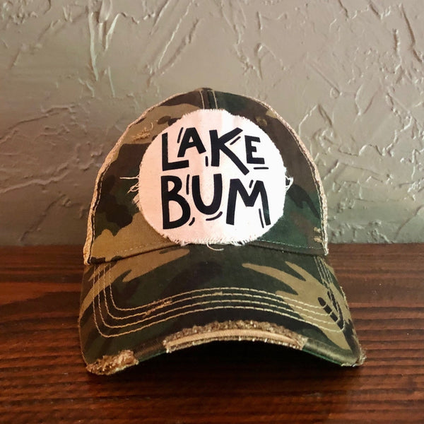 Lake Bum hat by BohoGroove with black Lake Bum lettering on distressed off-white patch on a camo vintage distressed snapback.