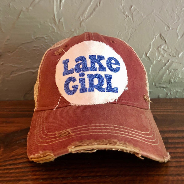 Lake Girl glitter hat by BohoGroove with blue glitter Lake Girl lettering on distressed off-white patch on a brick red vintage distressed snapback.