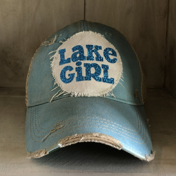 Lake Girl glitter hat by BohoGroove with blue glitter Lake Girl lettering on distressed off-white patch on an ocean blue vintage distressed snapback.