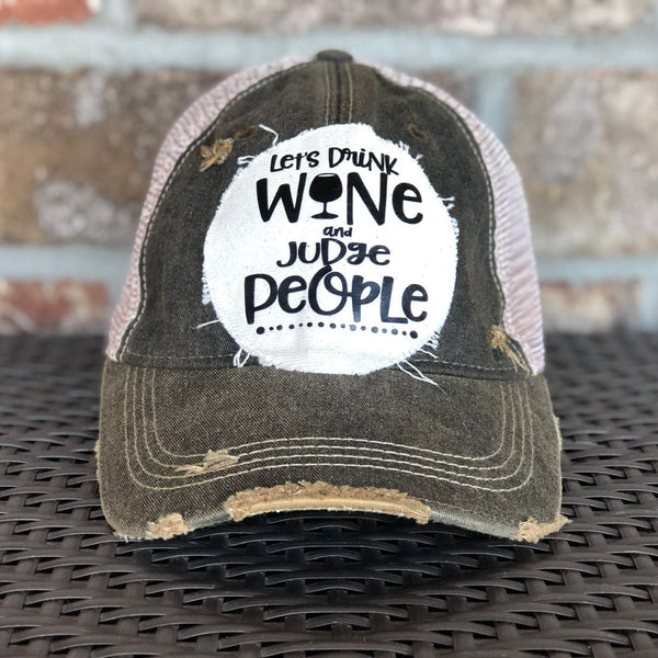 Let’s Drink Wine and Judge People hat by BohoGroove featuring whimsical black lettering with a wine glass graphic on a distressed off-white patch on a black vintage distressed snapback trucker hat.
