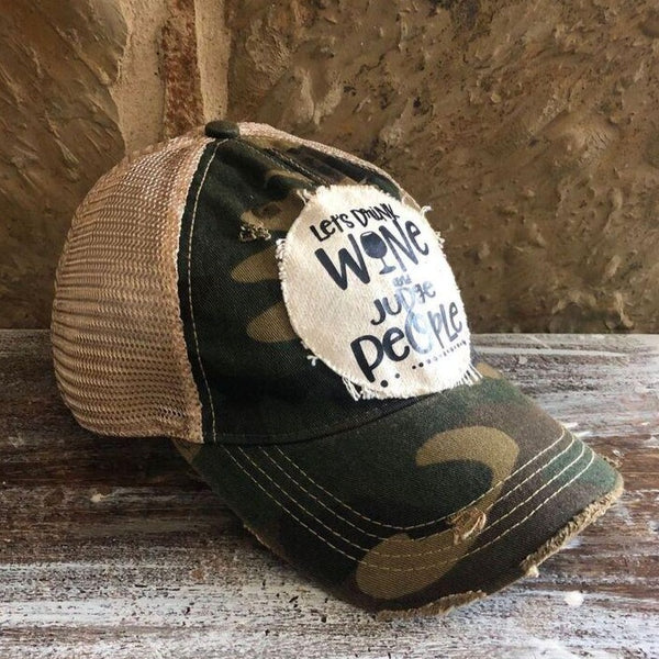 Left side view of the Let’s Drink Wine and Judge People hat by BohoGroove on a camo vintage distressed snapback trucker hat with distressed off-white patch.