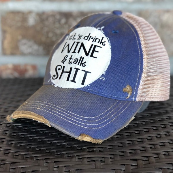 Right side view of the Let’s Drink Wine and Talk Shit hat by BohoGroove with black lettering on a distressed off-white patch on a royal blue vintage distressed snapback trucker hat.