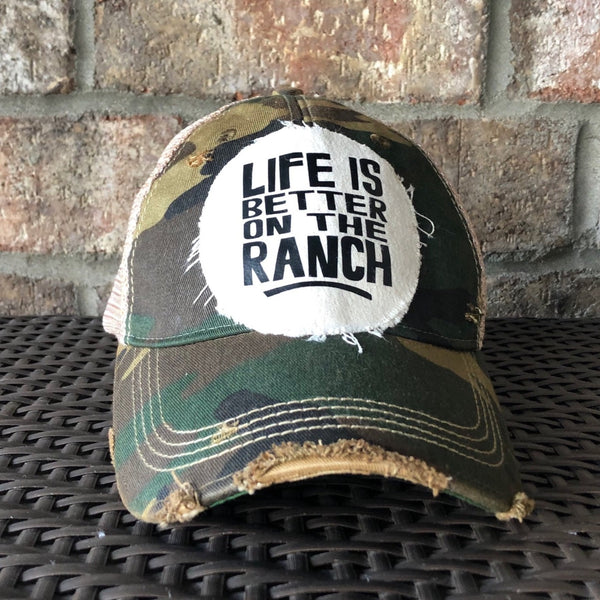 Life Is Better on the Ranch hat by BohoGroove with black Life Is Better on the Ranch lettering on a distressed off-white patch on a camo vintage distressed snapback.