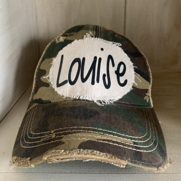 Louise hat by BohoGroove with black Louise lettering on a distressed off-white patch on a camo vintage distressed snapback.