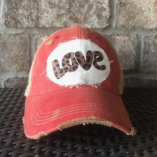 Love hat by BohoGroove with leopard print Love lettering on a distressed off-white patch on red vintage distressed snapback trucker hat.