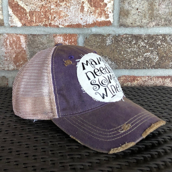 Left side view of Mama Needs Some Wine hat by BohoGroove featuring whimsical black script lettering on a distressed off-white patch on a purple vintage distressed snapback trucker hat.