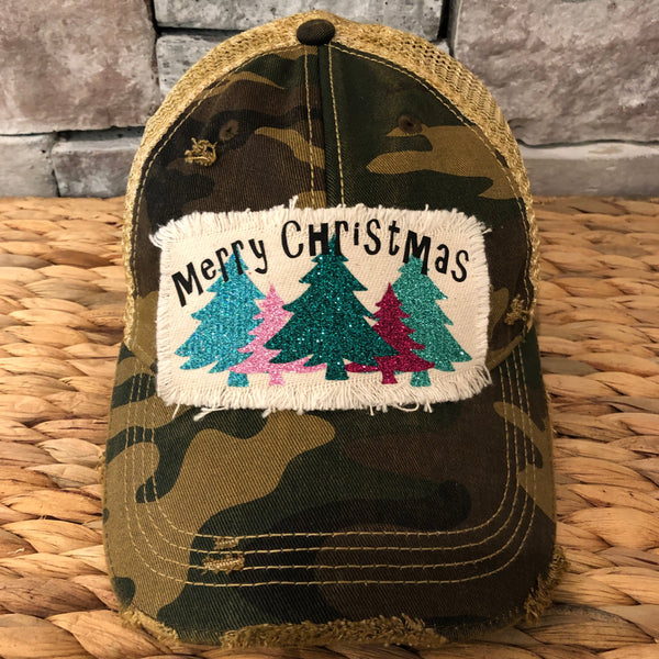 Merry Christmas hat by BohoGroove with black Merry Christmas lettering and five glitter Christmas trees in turquoise, pink, dark green, red, and mint on a distressed off-white patch on a camo vintage distressed snapback.