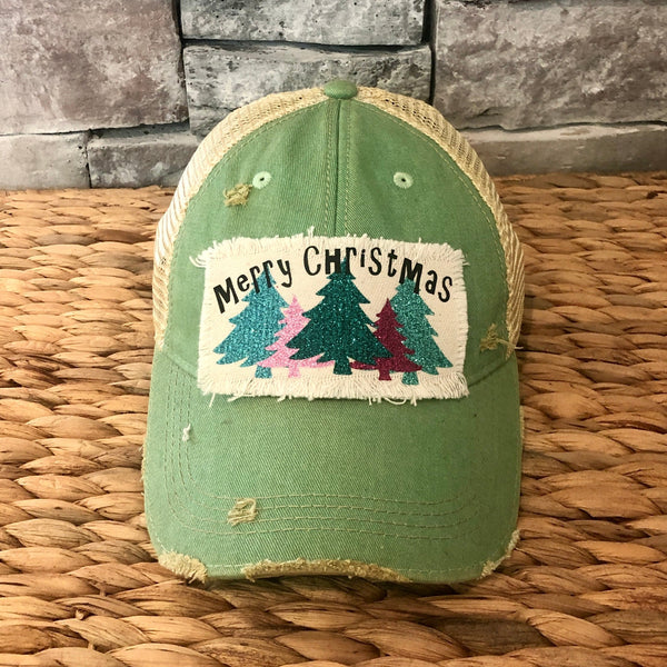 Merry Christmas hat by BohoGroove with black Merry Christmas lettering and five glitter Christmas trees in turquoise, pink, dark green, red, and mint on a distressed off-white patch on a mint vintage distressed snapback.