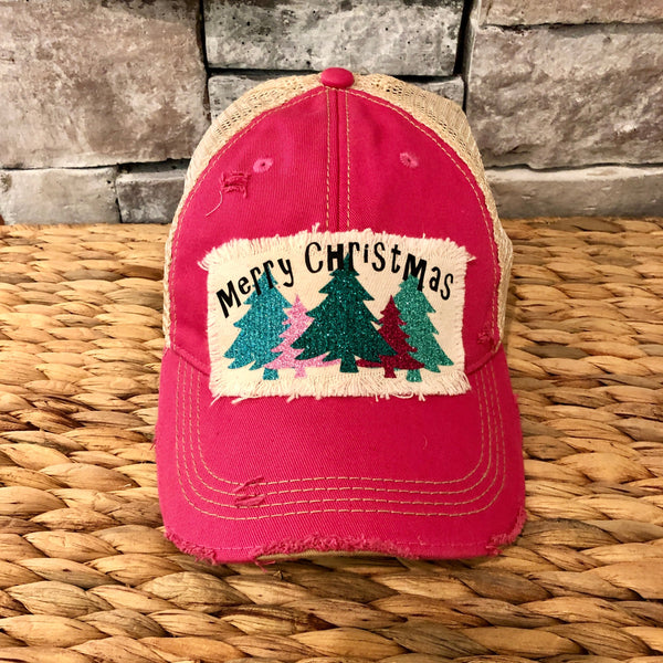 Merry Christmas hat by BohoGroove with black Merry Christmas lettering and five glitter Christmas trees in turquoise, pink, dark green, red, and mint on a distressed off-white patch on a pink vintage distressed snapback.