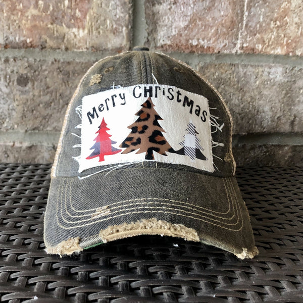 Merry Christmas Trees hat by BohoGroove with black Merry Christmas lettering and three Christmas tree graphics featuring red plaid, leopard print, and black buffalo plaid designs on a distressed off-white custom patch on a black vintage distressed snapback.