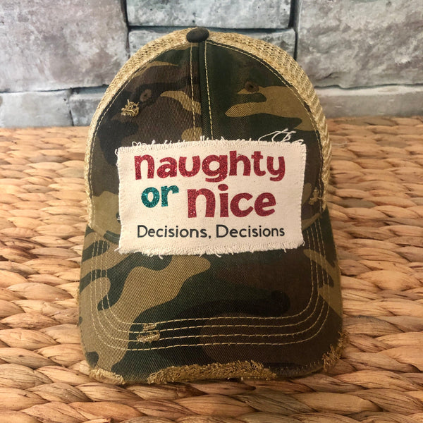 Naughty or Nice hat by BohoGroove with red and green Naughty or Nice lettering and Decisions, Decisions wording on a distressed off-white patch on a camo vintage distressed snapback.