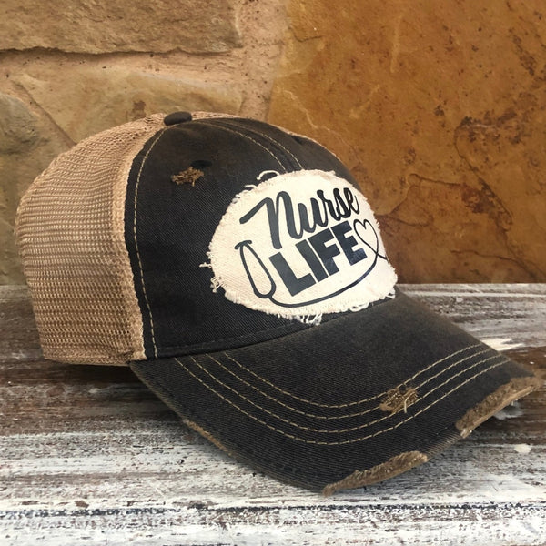 Left side view of the Nurse Life hat by BohoGroove featuring black Nurse Life lettering, stethoscope graphic, and heart detail on a distressed off-white patch on a black vintage distressed snapback.