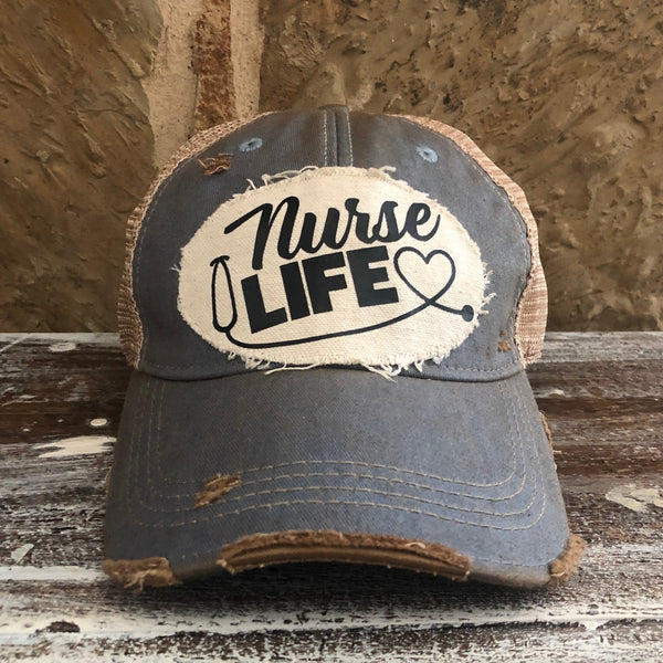 Nurse Life hat by BohoGroove with black Nurse Life lettering, stethoscope graphic, and heart detail on a distressed off-white patch on a light blue vintage distressed snapback.