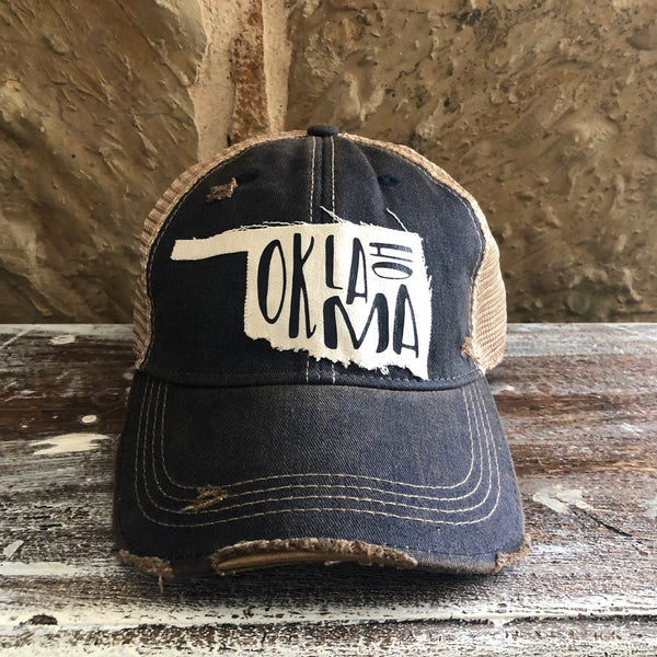 Oklahoma hat by BohoGroove with black Oklahoma lettering on a distressed off-white patch in the shape of the state of Oklahoma on a navy vintage distressed snapback.